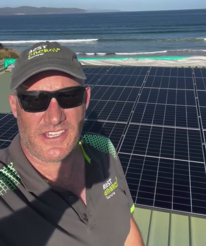 George from REST Energy on a Clifton Beach roof with the solar array and beach behind