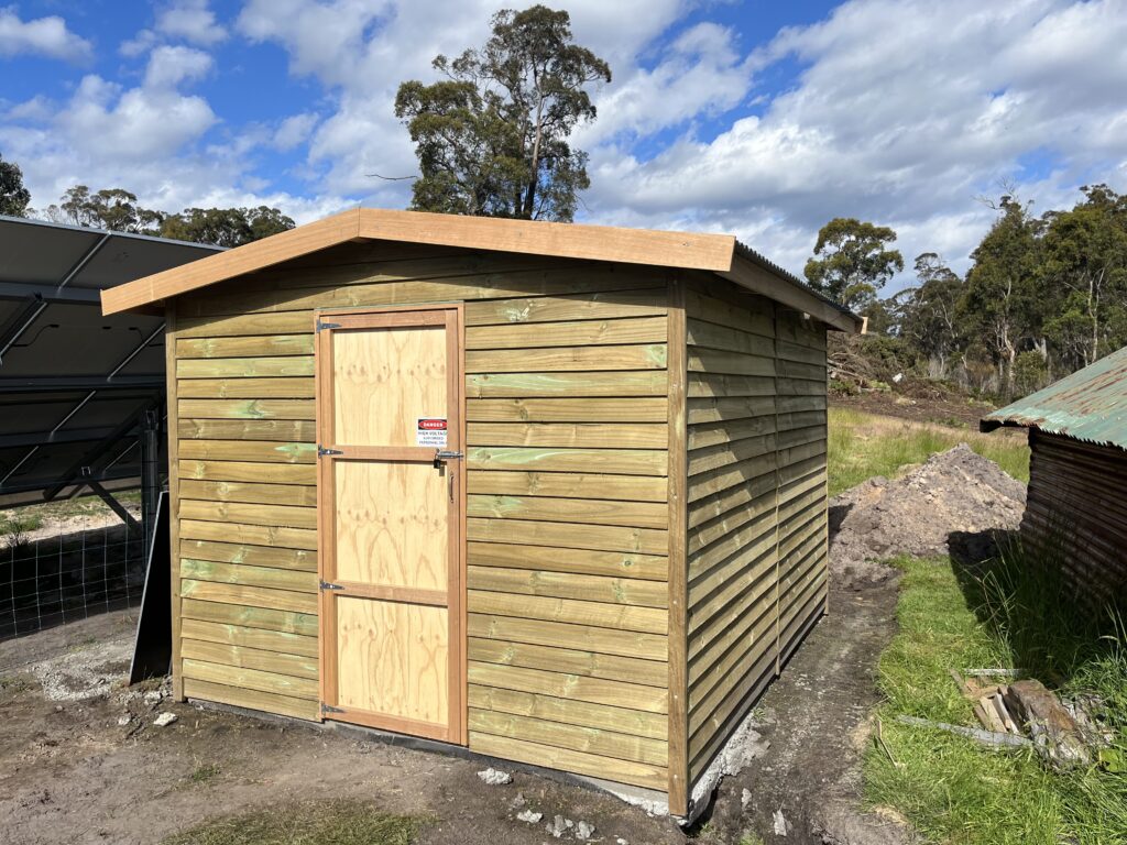 Custom off-grid solar equipment shed built by REST Energy