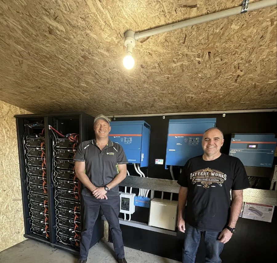 George from REST Energy beside a battery rack and Victron inverters in a battery room