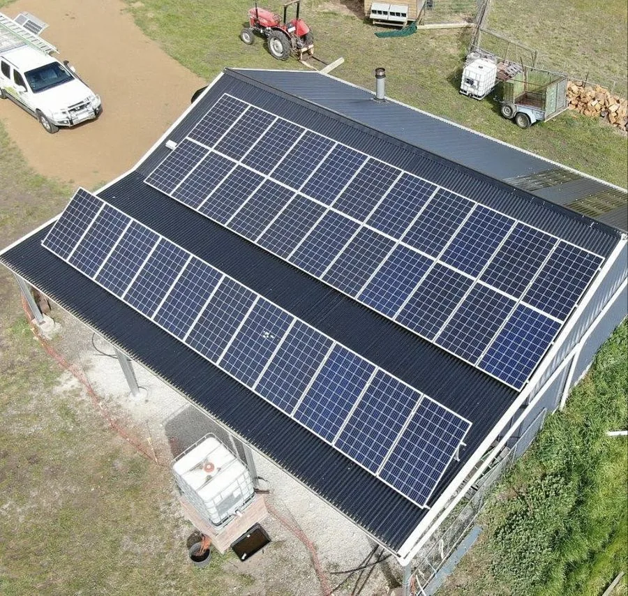 Aerial view of solar panels on a rural shed roof with farm paddocks around it